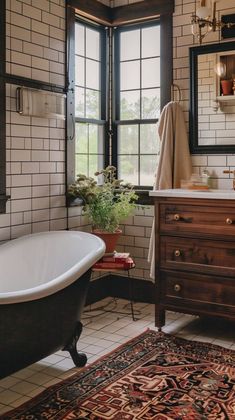 a bath tub sitting next to a sink in a bathroom under two large windows and a rug on the floor