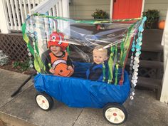 two children in a plastic toy car on the sidewalk