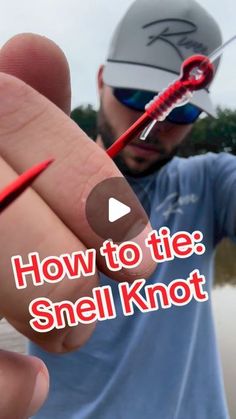 a man holding a red fishing hook in his right hand with the words how to tie smell knot on it