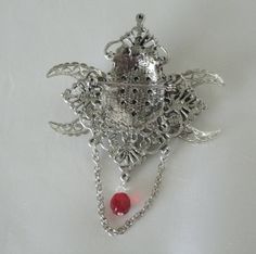 Triple Moon Brooch This beautiful silver plated brooch has silver plated crescent moons, a red setting, rhinestones, metal chain, seed beads and red faceted glass bead. Can also be worn as a cloak pin. It is 2.75 inches wide and 3.75 inches long with bead drop and chain. Silver Brooch Jewelry For Halloween, Gothic Brooch Jewelry Gift, Gothic Halloween Brooch Jewelry, Halloween Gothic Brooch Jewelry, Spiritual Silver Jewelry Brooch, Spiritual Silver Brooch, Spiritual Silver Brooch For Gift, Cloak Pin, Wicca Jewelry