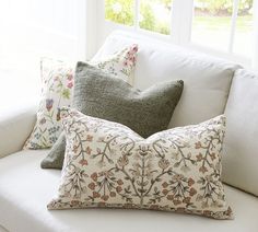 a white couch with pillows on it in front of a window