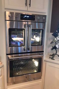 a kitchen with white cabinets and stainless steel ovens in the corner, along with other appliances