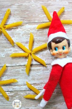 an elf doll laying next to bananas on a wooden table with yellow peels in the background