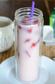 a glass filled with liquid sitting on top of a white plate next to a cup