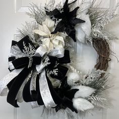 a wreath with white flowers and black ribbons