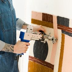 a person is using a machine to fix a piece of art on the wall in front of them