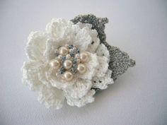 two crocheted flowers with pearls on them sitting on top of a white surface