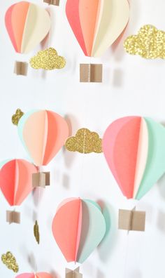 paper hot air balloons are hanging from clothes pins on a string with gold glitters