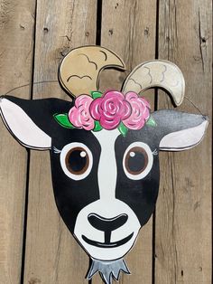 a goat mask with flowers on it's head sitting on a wooden fence post