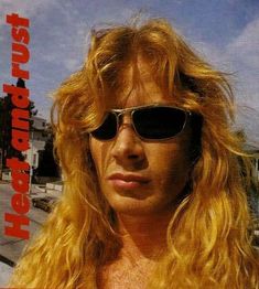 a man with long blonde hair and sunglasses on top of his head looking at the camera