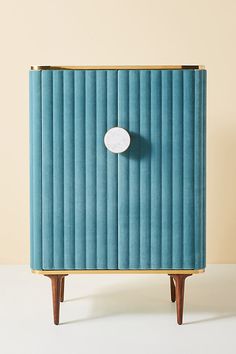 a blue cabinet sitting on top of a white floor next to a wall with a round button