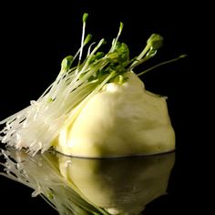 a piece of artichoke sitting on top of a black table next to water