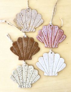 three seashell ornaments are hanging from string