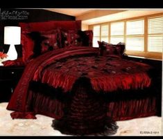 a bed with red and black comforters in a room next to a lamp on a table