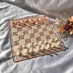 a chess board and flowers on a white sheet with orange petals in the foreground