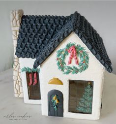 a small white house with a wreath on the roof and door is decorated for christmas