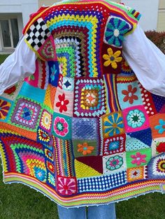 a woman is holding up a colorful crocheted blanket