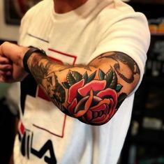 a man with a rose tattoo on his arm and hand is holding something in his other hand