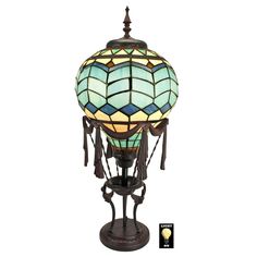 a stained glass lamp with tassels on the top and bottom, sitting on a stand