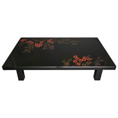 a black coffee table with red flowers on the top and bottom, against a white background