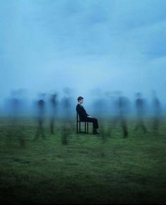 a man sitting on top of a chair in the middle of a field