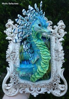 an ornate frame with a green dragon in it's center and blue feathers on its back