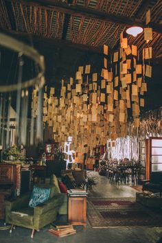 a living room filled with furniture and lots of wooden squares hanging from the ceiling above