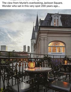 tables and chairs are set outside on the balcony overlooking an old building at night time