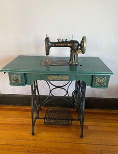 an old sewing machine sitting on top of a green table next to a white wall