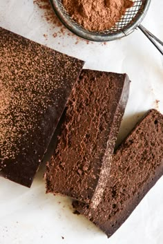 three pieces of chocolate cake next to a scoop of cocoa powder