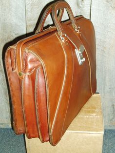 Classic ,Top Open,Valise style ,briefcase made from top quality USA tanned bridle leather.Also sometimes refered to as a Lawyers Briefcase,this beautiful, but rugged case measures approx 16.5x14x6 inches. It's in stock in black with chrome hardware or brown with solid brass hardware, and keyed lock.It has 2 dividers inside, making 3 equal sized compartments.Other colors and sizes available on special order. Like all our products, it's created one at a time in Montana, USA, using only the best ma Lawyer Briefcase, Black With Chrome, Carryon Bag, Montana Usa, Lock It, Comfortable Jeans, Chrome Hardware, Phone Holster, Leather Briefcase