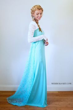 a woman in a long blue dress standing on a hard wood floor with her hand on her hip