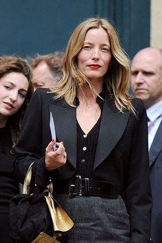 a woman holding a knife in her hand while walking down the street with other people behind her