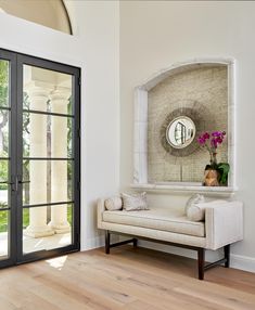 a white couch sitting in front of a mirror on a wall next to a doorway