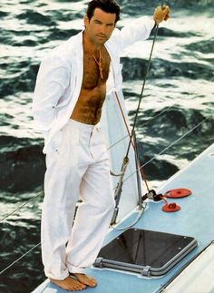 a shirtless man standing on top of a boat