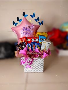 a gift box filled with chocolates, candies and balloons for someone's birthday