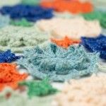 closeup of multicolored crocheted material on white surface