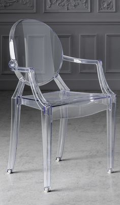 a clear plastic chair sitting in front of a wall