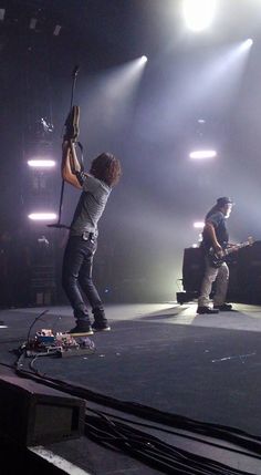 two men on stage with guitars and microphones in front of the audience at a concert