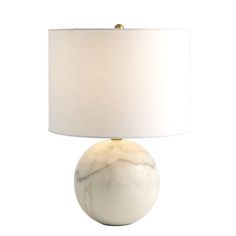 a white lamp with a gold base and a white shade on it's side