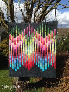 a colorful quilt hanging from a tree