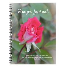 a spiral notebook with the words prayer journal written on it and a pink rose in bloom