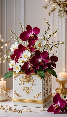 a white vase with purple and white flowers on a table next to two lit candles