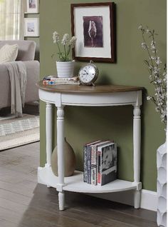 a white table with a clock and some books on it next to a couch in a living room