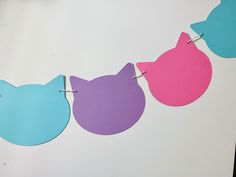 three pieces of paper cut out to look like cats hanging from clothes pins on a line