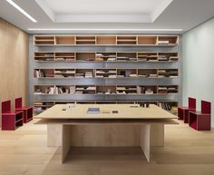 an empty room with bookshelves and desks in the center, surrounded by wooden flooring