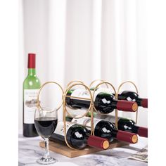 a wine rack with several bottles and two glasses on the table next to each other