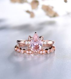 a pink diamond ring sitting on top of a white surface with flowers in the background