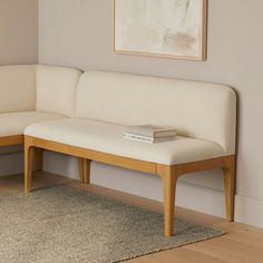 a white couch sitting on top of a wooden floor next to a painting above it