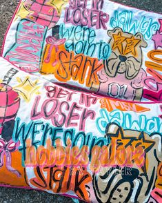 two pillows covered in graffiti sitting on top of a cement ground next to each other